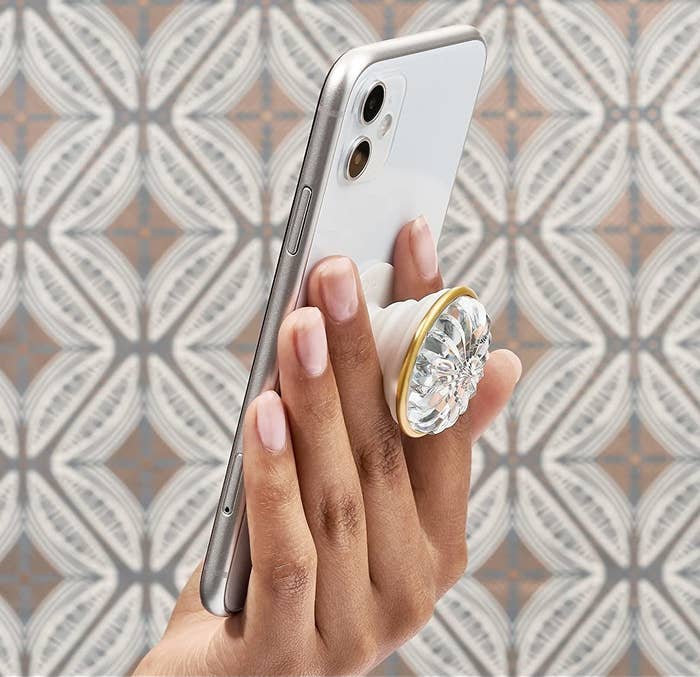 a person holding up a phone with the jewelled popsocket on the back