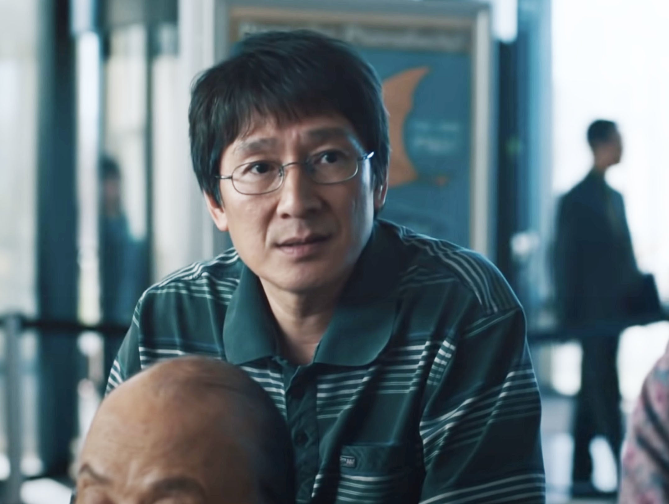 close up of Ke in a polo shirt and small oval shaped glasses