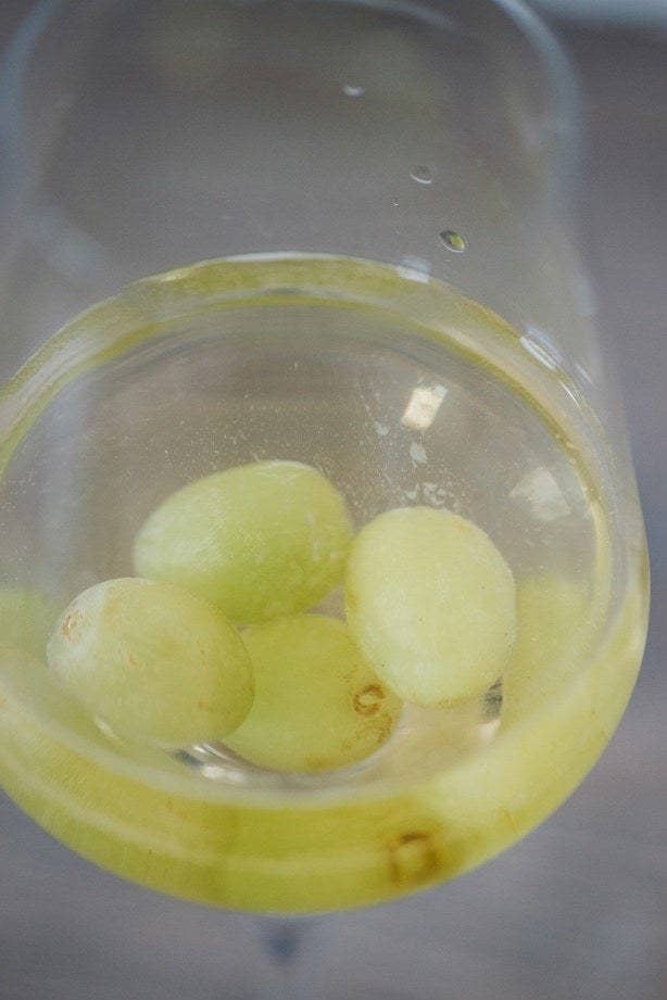 Frozen grapes in a glass of white wine