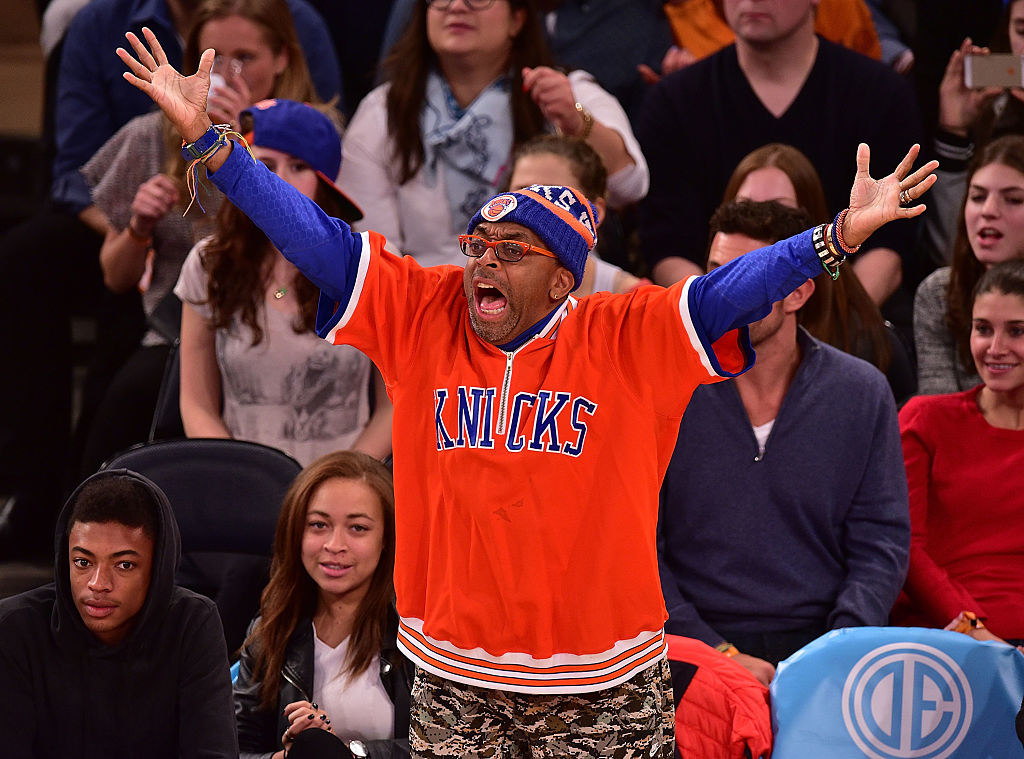 Spike standing up courtside and gesticulating angrily while wearing Knicks gear