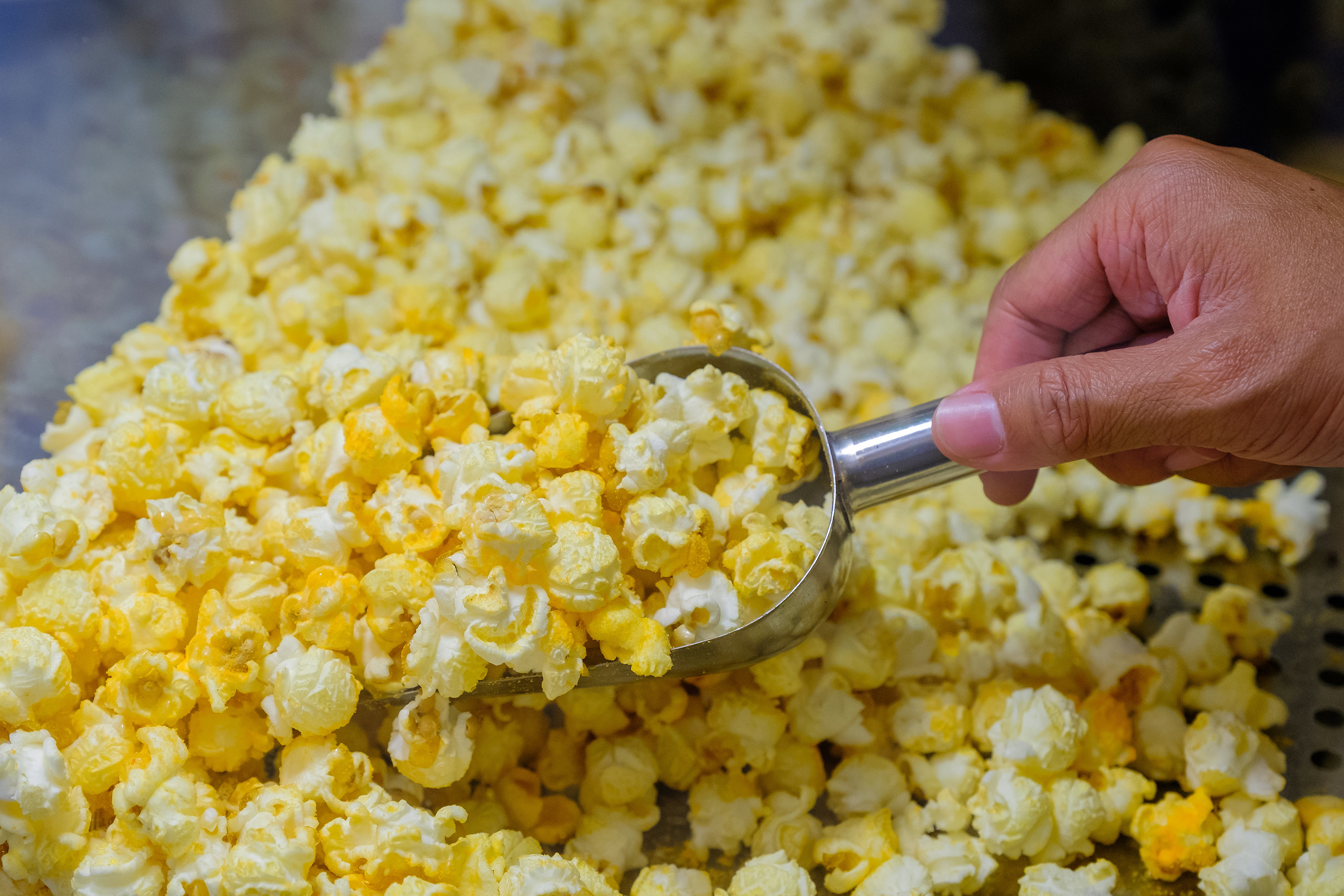 close up of a hand scooping up popcorn