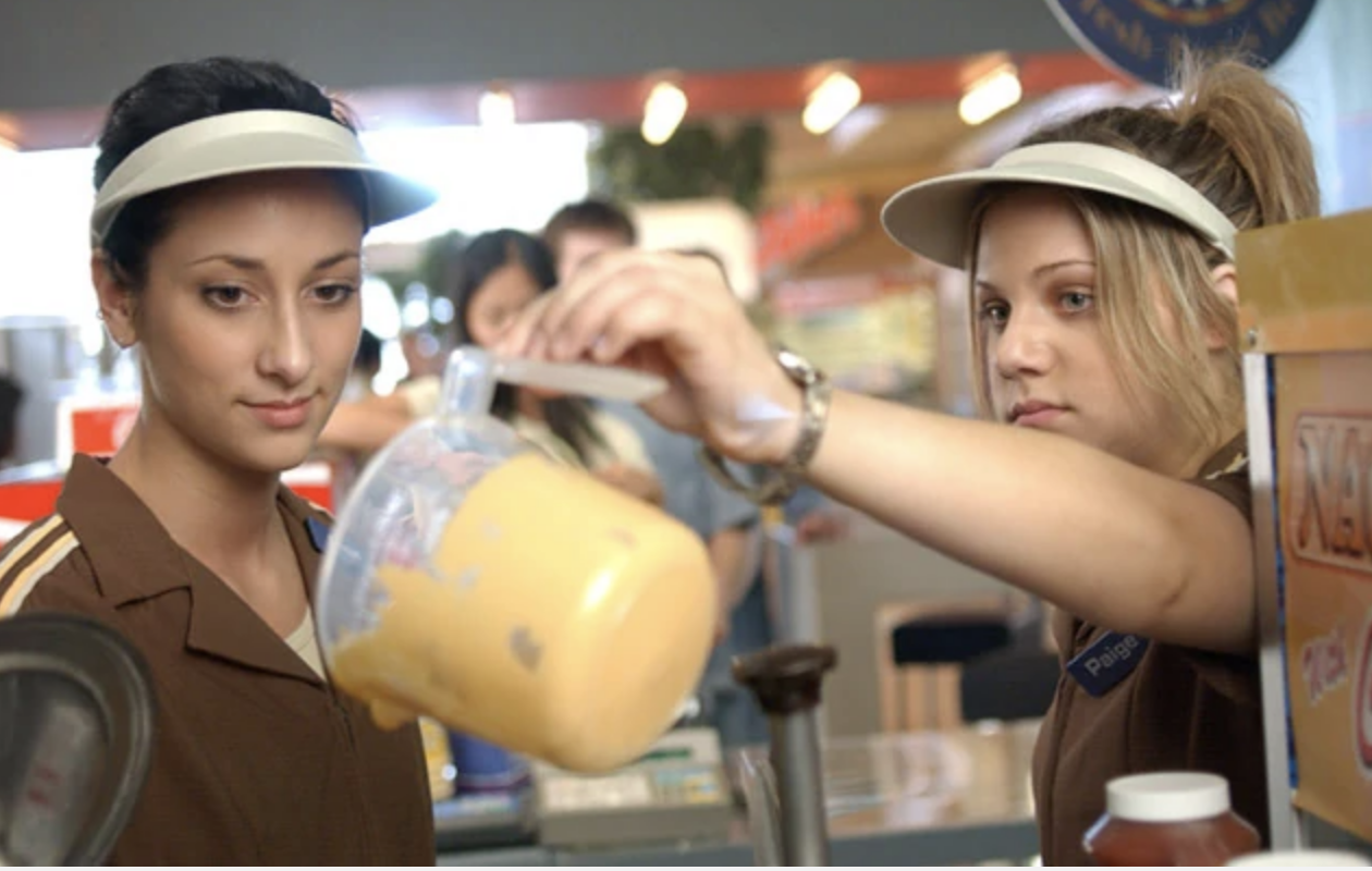 a character pouring out cheese behind the concessions stand