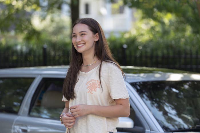 a girl standing by a car