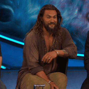 Jason Momoa smiling and turning in his chair