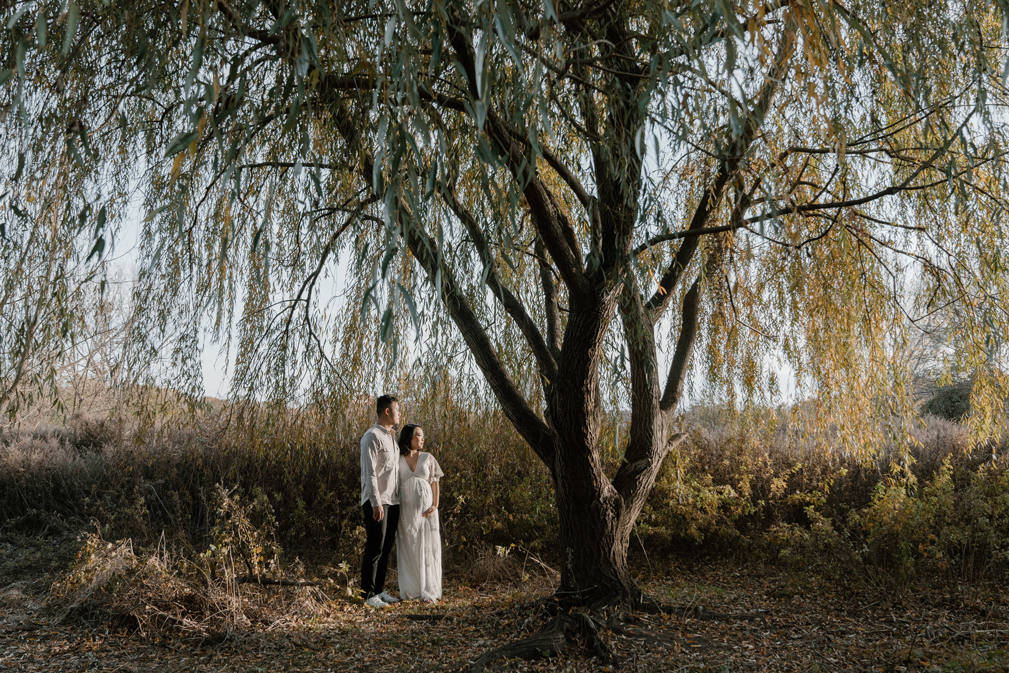 A man and woman standing by a tree