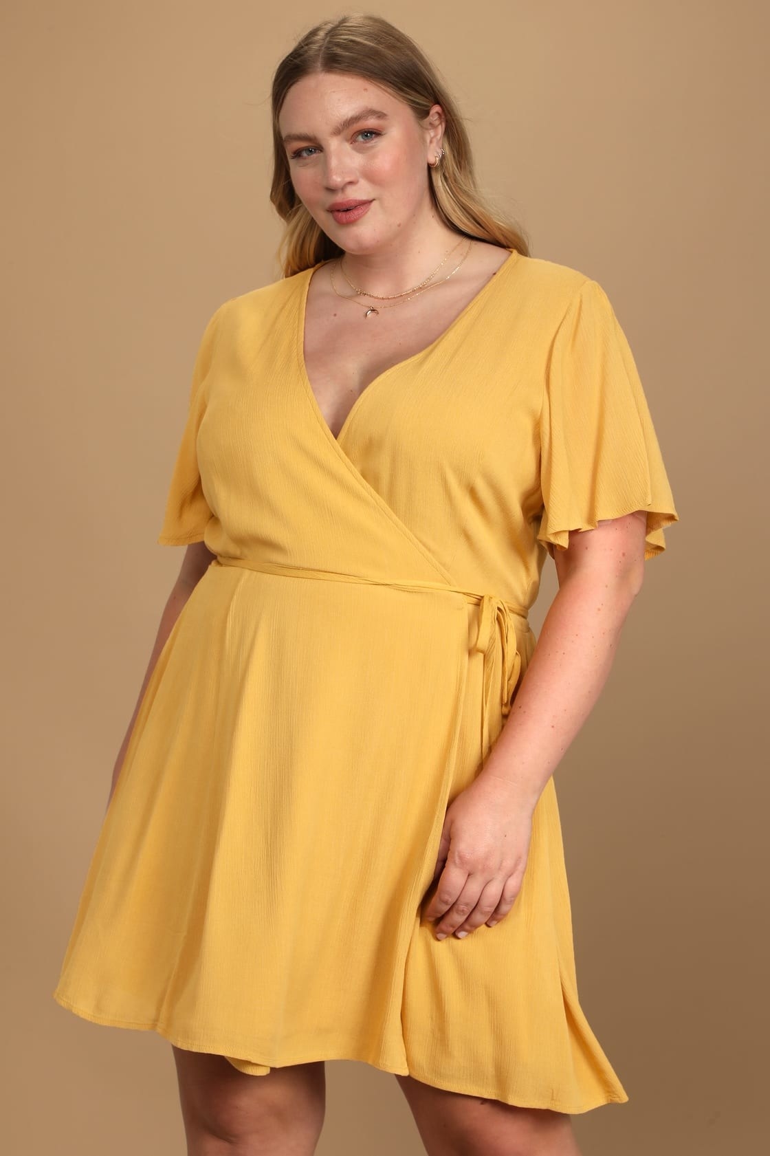 model in yellow wrap mini dress with fluttery sleeves