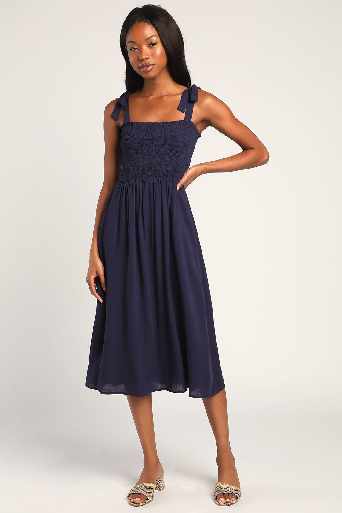 model in navy blue midi dress with smocked top and narrow tie straps