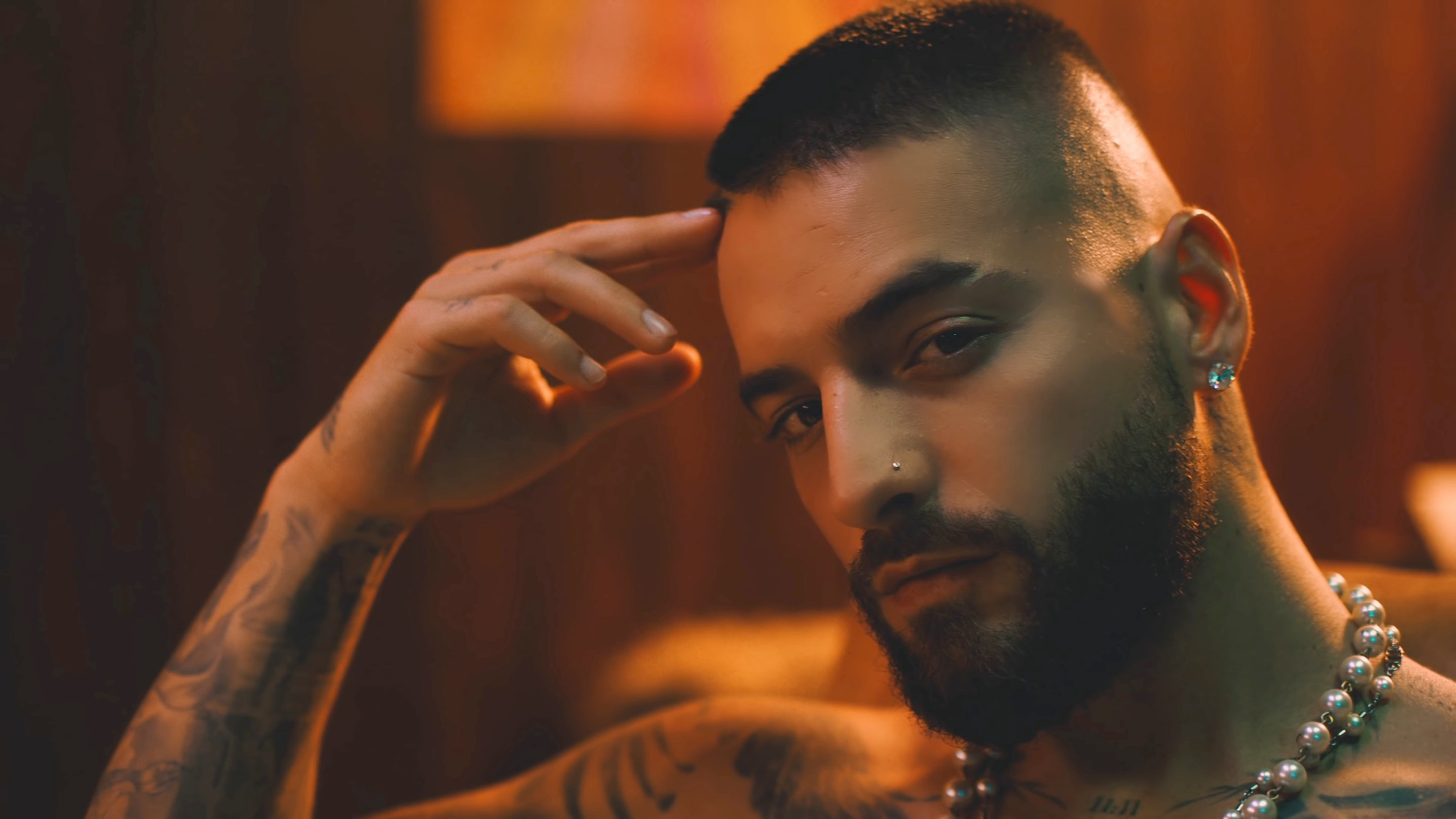 Maluma looking sultry and into the camera while touching his forehead