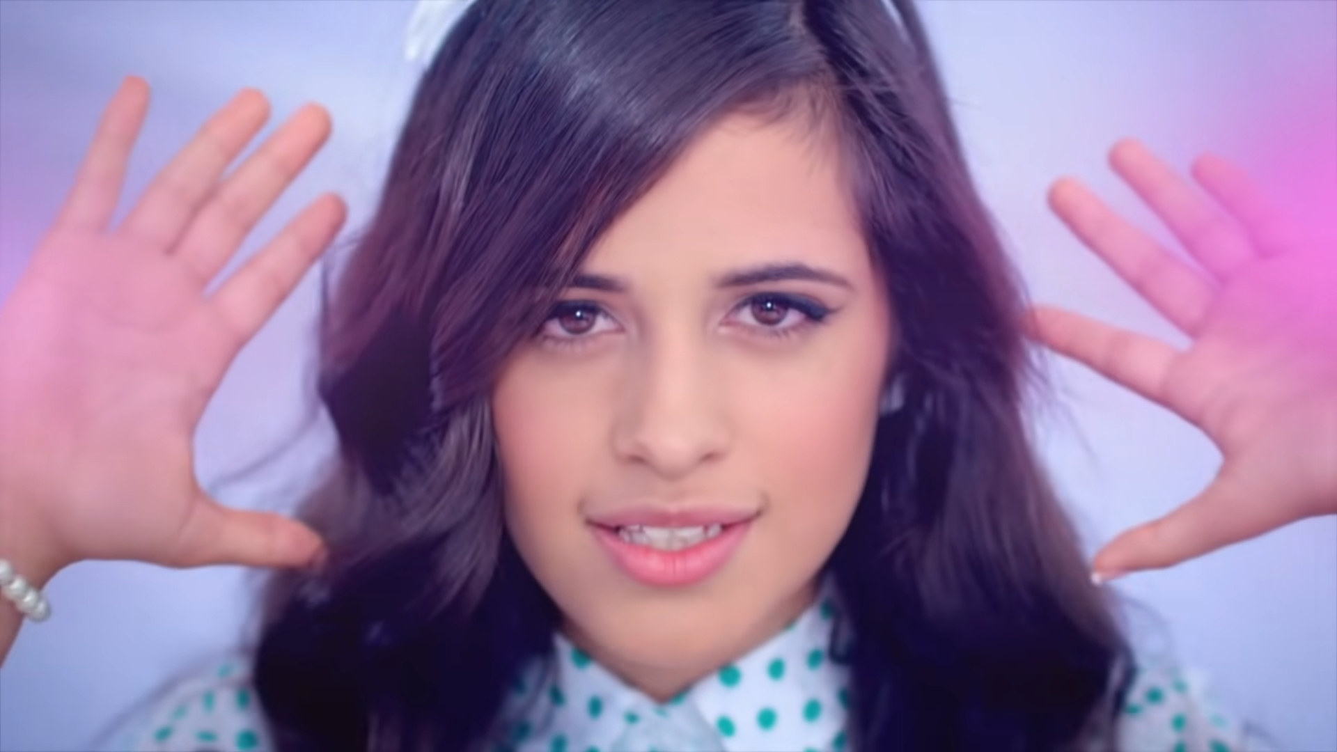 Headshot of Camila holding her hands up