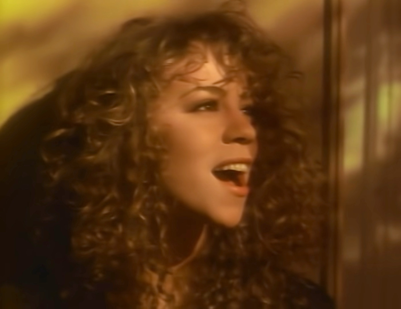 Headshot of Mariah with curly hair singing