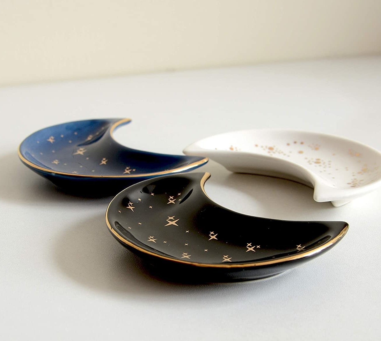 three moon-shaped trinket dishes on a white surface