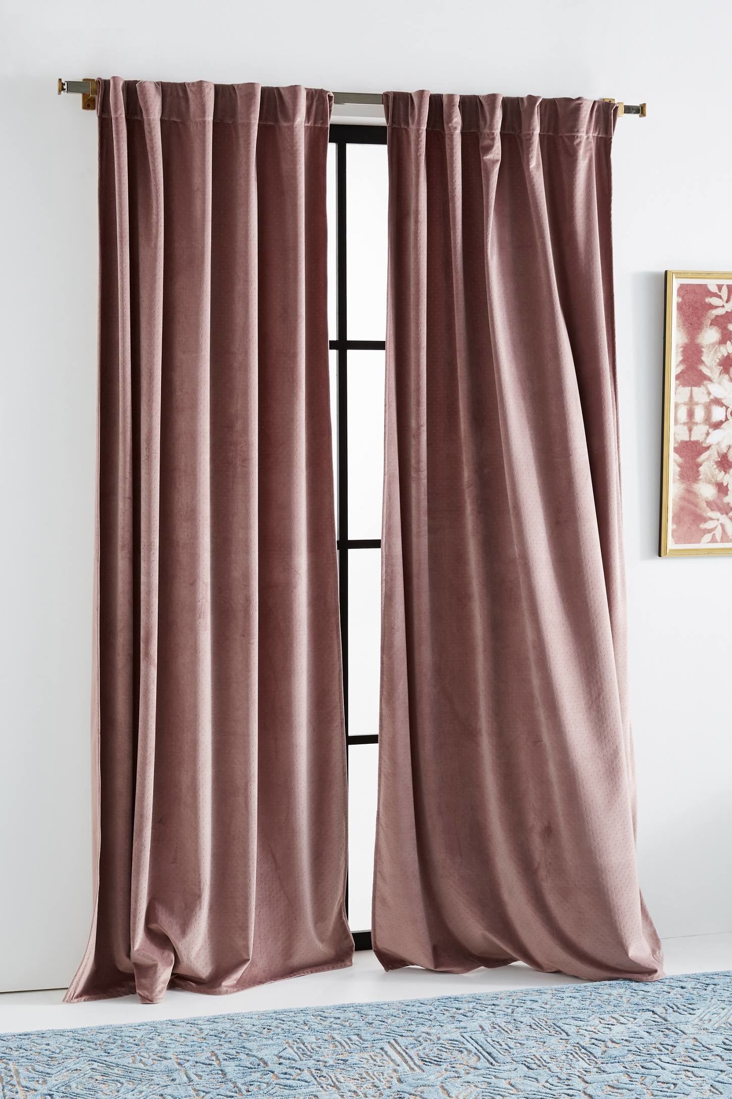 a set of dusty pink velvet curtains hung above a window