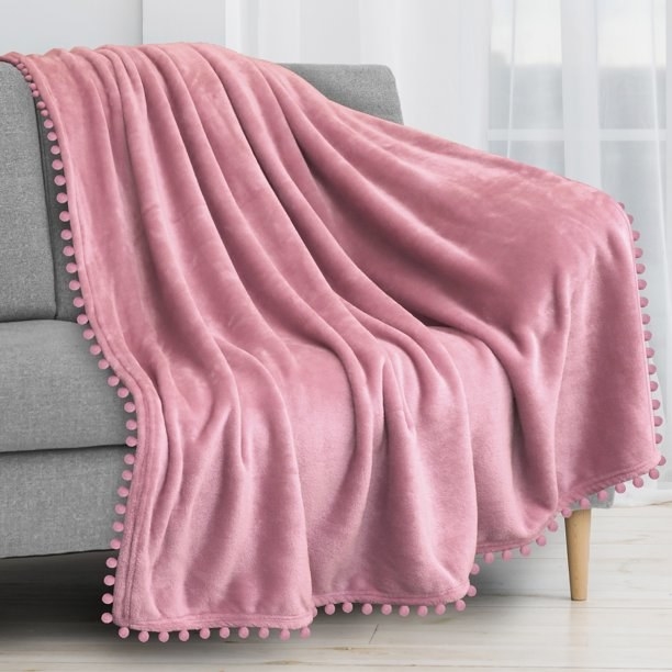 the pink fuzzy blanket draped over a grey couch
