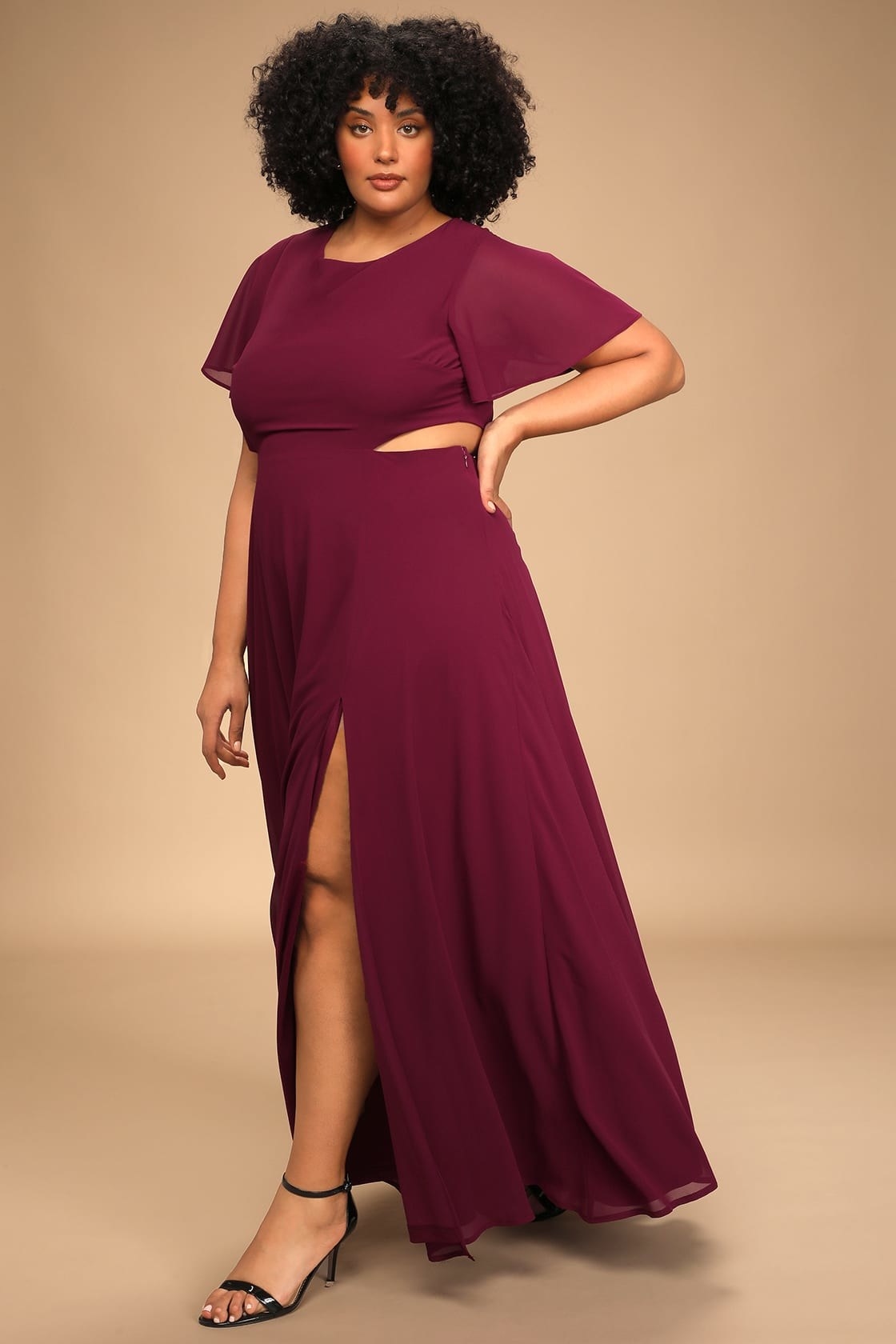 model in burgundy maxi dress with a slit, cutout across the back and sides, and fluttery sleeves