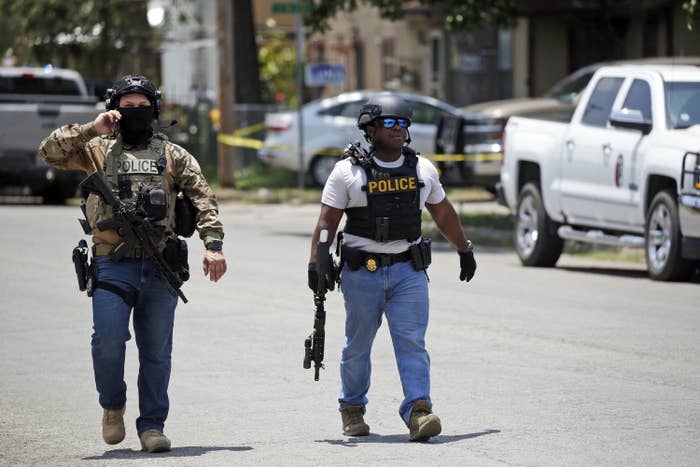 Two police officers with guns walk near the Robb Elementary school in Uvalde