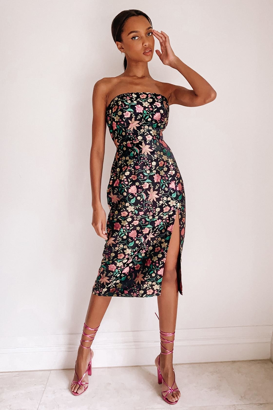 model in black strapless midi dress in a floral jacquard fabric with a slit
