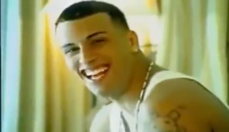 Nicky, with a close-cropped haircut and in a sleeveless shirt, smiling at the camera