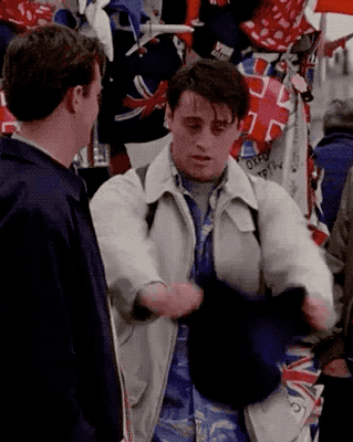 Joey from Friends putting on a large felt souvenir hat with a British flag on it