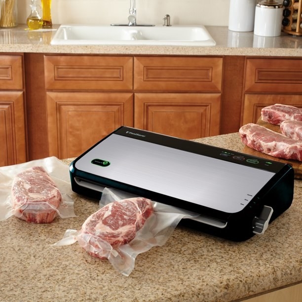 the silver vacuum sealer machine with several steaks on a counter