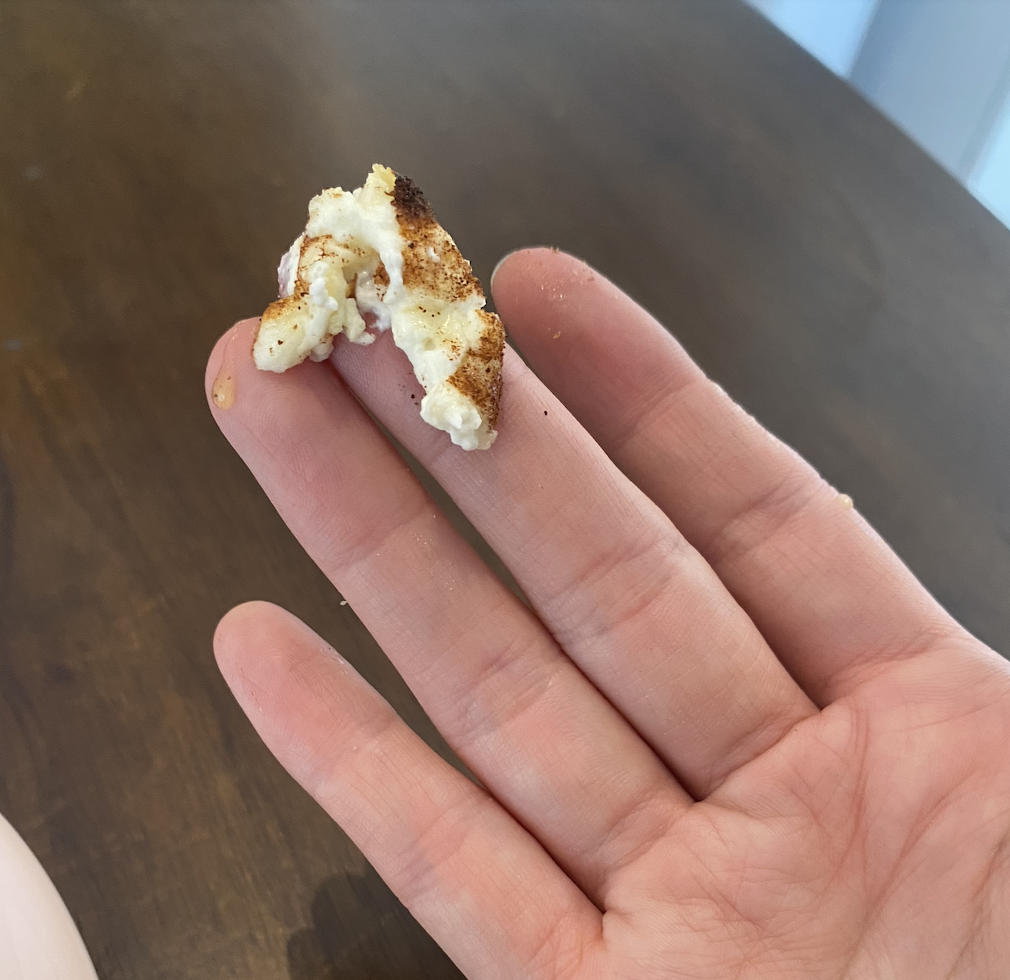A bit of cream cheese with cinnamon on it held on a finger