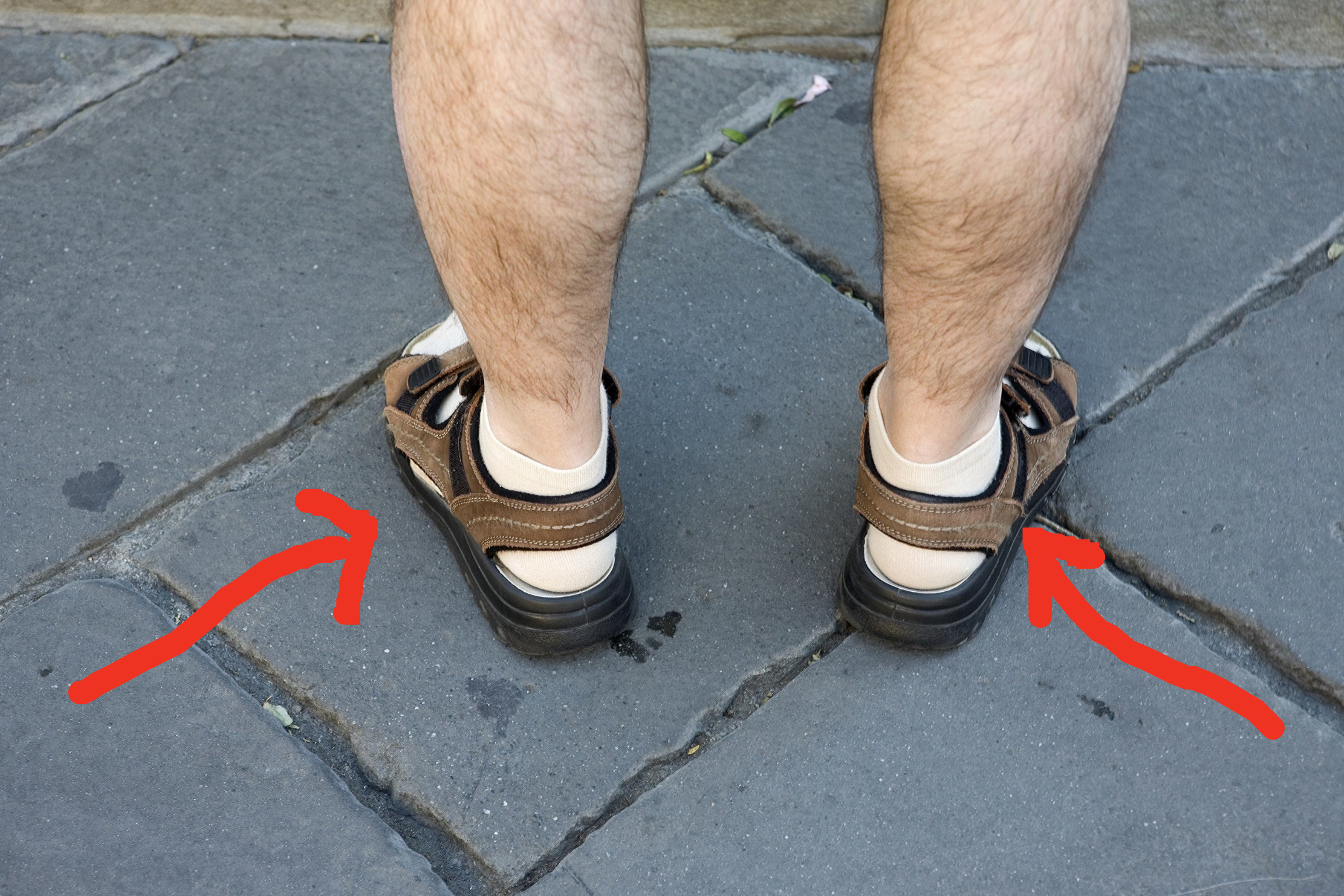 arrows pointing to a person wearing socks with their sandals
