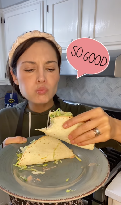 Woman picking up a taco off a plate with the text &quot;So good&quot;