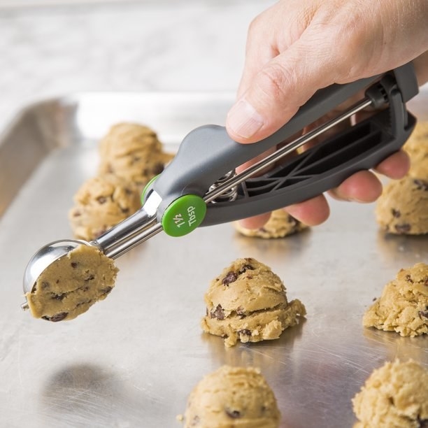 a model using the scoop to portion out chocolate chip cookie dough