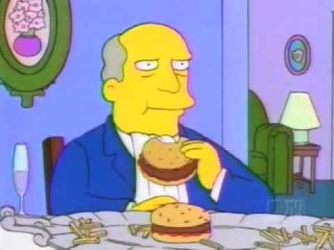 Superintendant Chalmers sits at a table, a platter of burgers and fries in front of him, he&#x27;s taking a bite