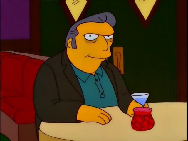 Fat Tony sits at a restaurant table, holding a martini and looking sinister