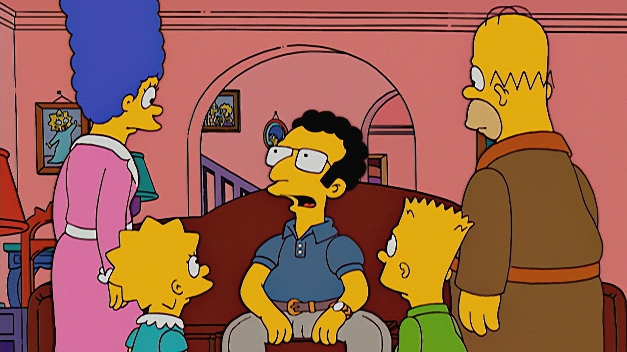 The Simpsons family stands around Artie Ziff, a nerdy looking guy who is sitting on their couch