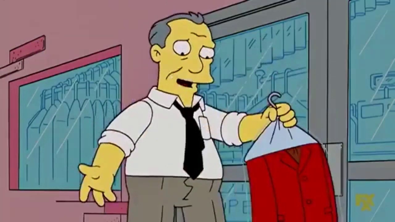 Gil stands in a shabby suit and undone tie, holding a red blazer in a dry cleaning bag