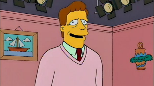 Troy McClure stands in a TV set version of the Simpsons&#x27; lounge room