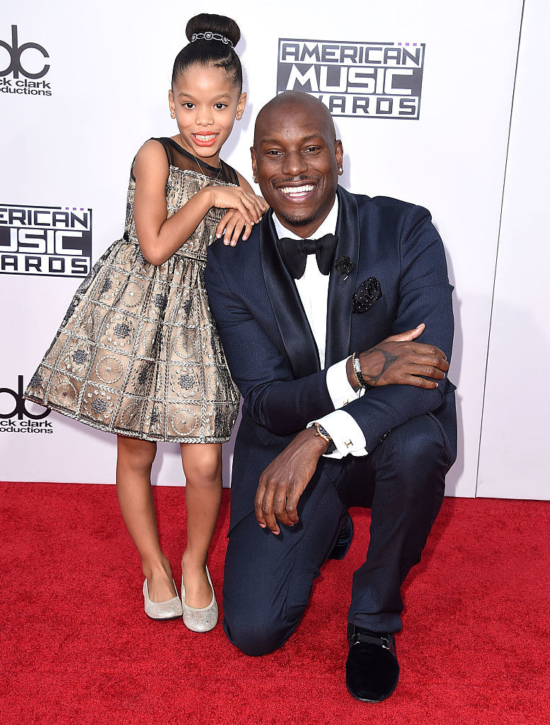 Tyrese Gibson wears a dark suit and Shayla Somer Gibson wears a sleeveless shiny dress