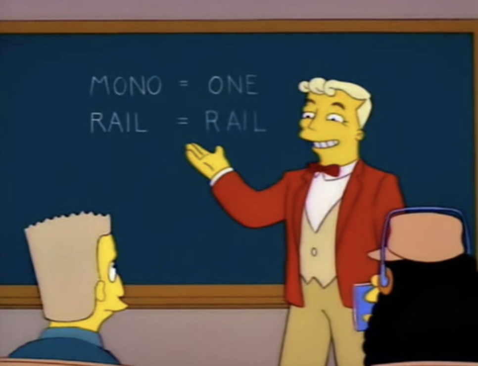 Lyle Lanley, in a red jacket and a red bow tie, stands in front of a black board that reads &#x27;mono = one, rail = rail&#x27;