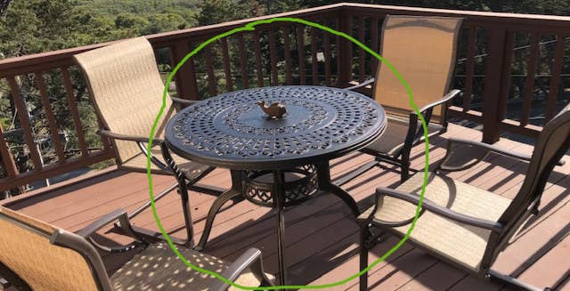 Reviewer image of black wrought iron patio table with rounded legs and four chairs surrounded