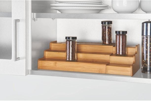 the wooden shelf with a few spice bottles in a cabinet