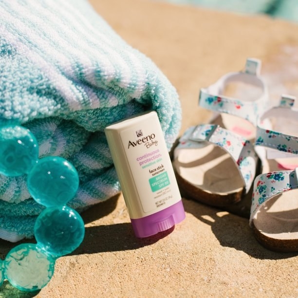 Sunscreen stick next to a towel and baby shoes