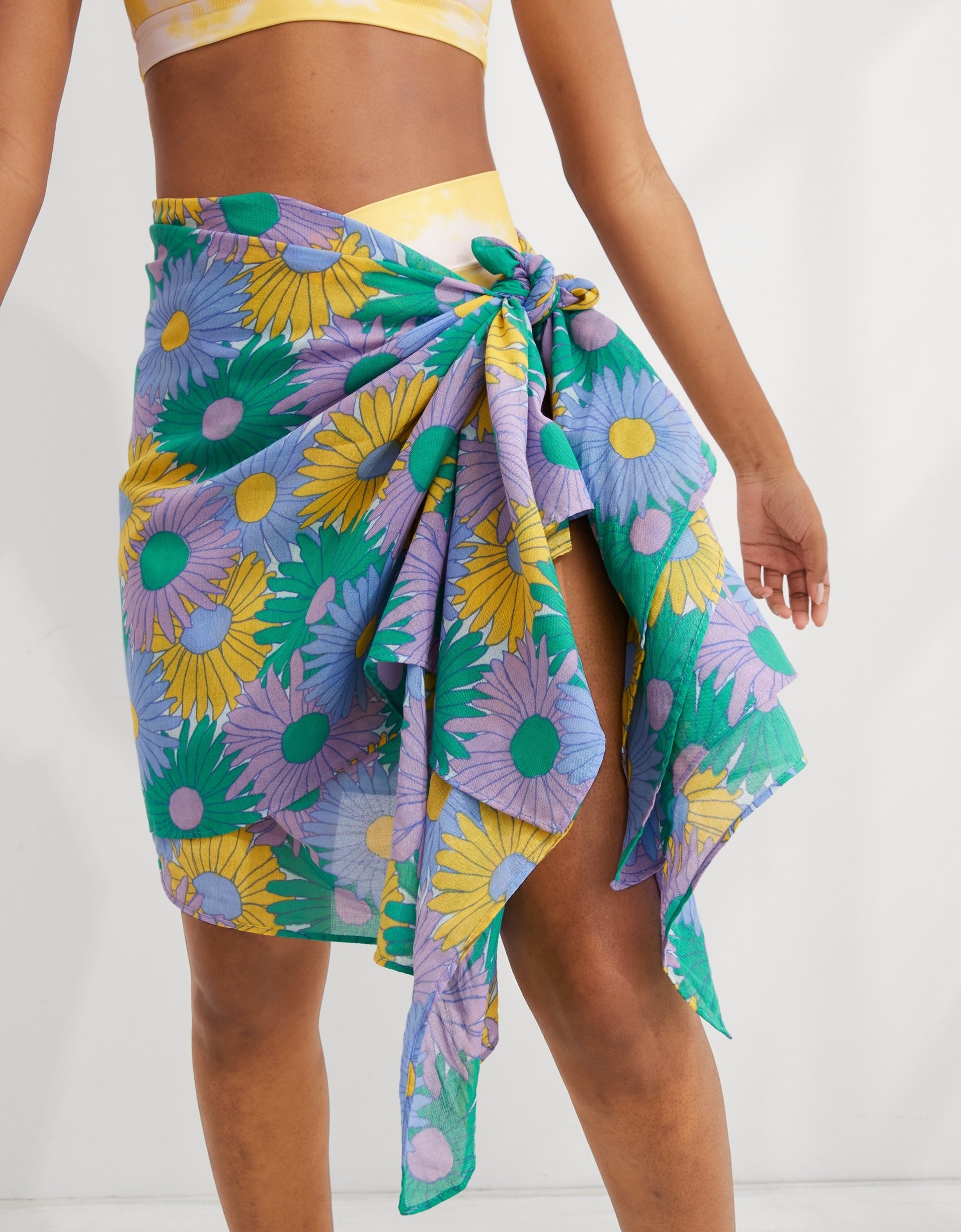 model wearing a lilac, yellow, green, and periwinkle sarong over a bikini