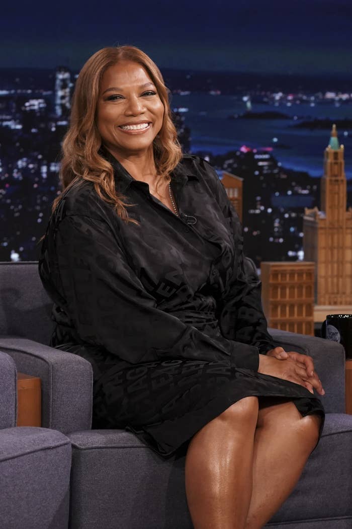 Queen Latifah smiling as she sits during a late-night TV show interview