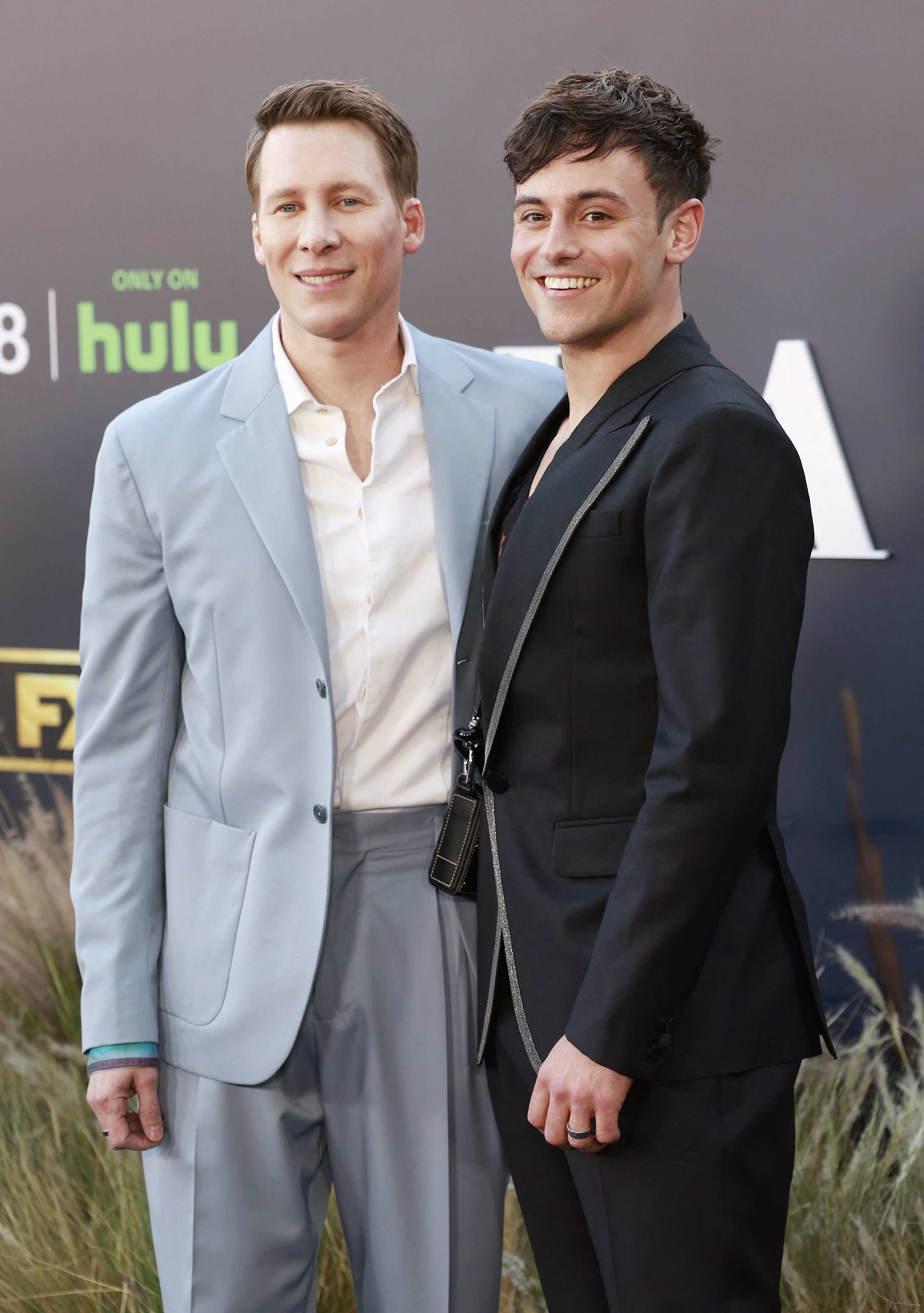 Tom Daley and Justin Lance Black stand together in suits