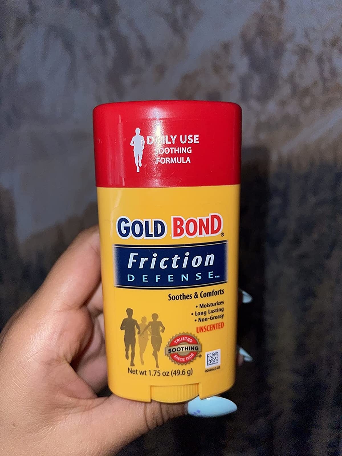 reviewer holding up a gold bond friction defense tube