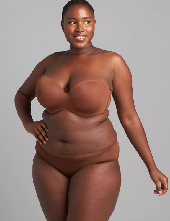 An image of a model wearing a brown strapless bra with hook and eye closure plus adjustable straps