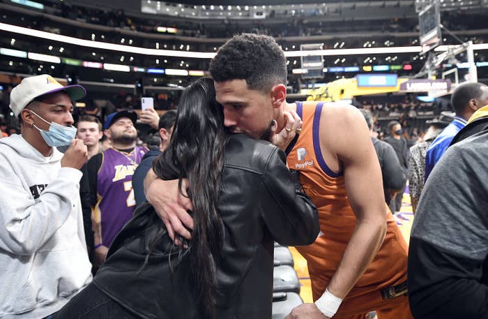 Kendall Jenner hugs Devin Booker, who&#x27;s wearing a jersey, at a basketball game