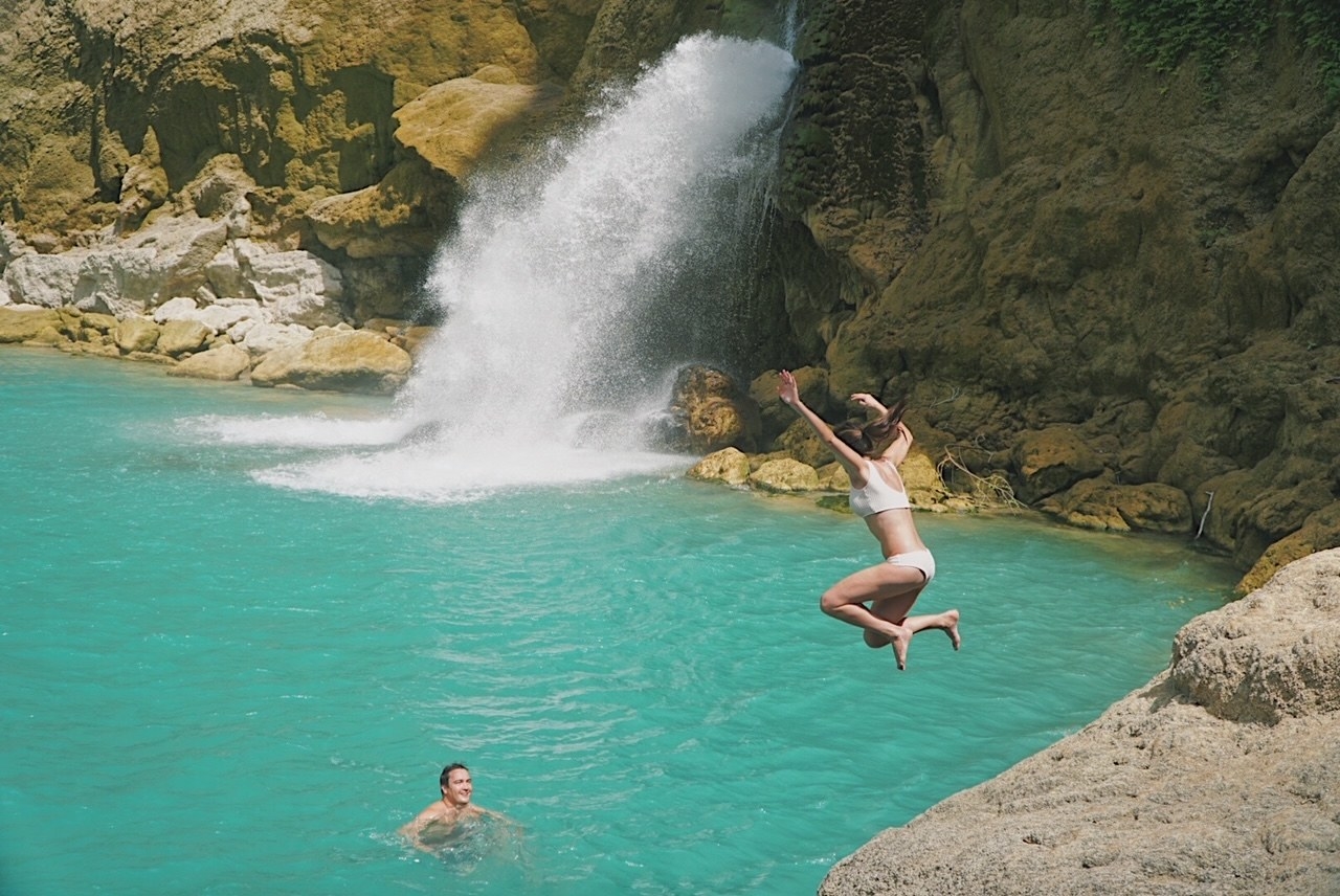 A woman jumping into a body of water where a man is waiting