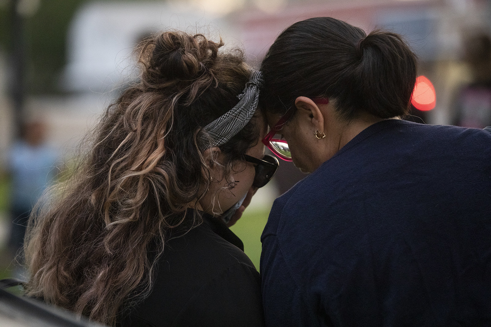 Two people hold their heads against each other as they sit and pray