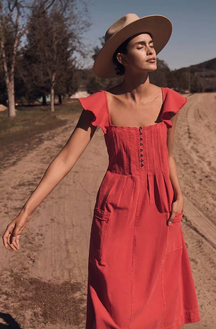 Model wearing scarlet colored midi dress with tan brimmed hat
