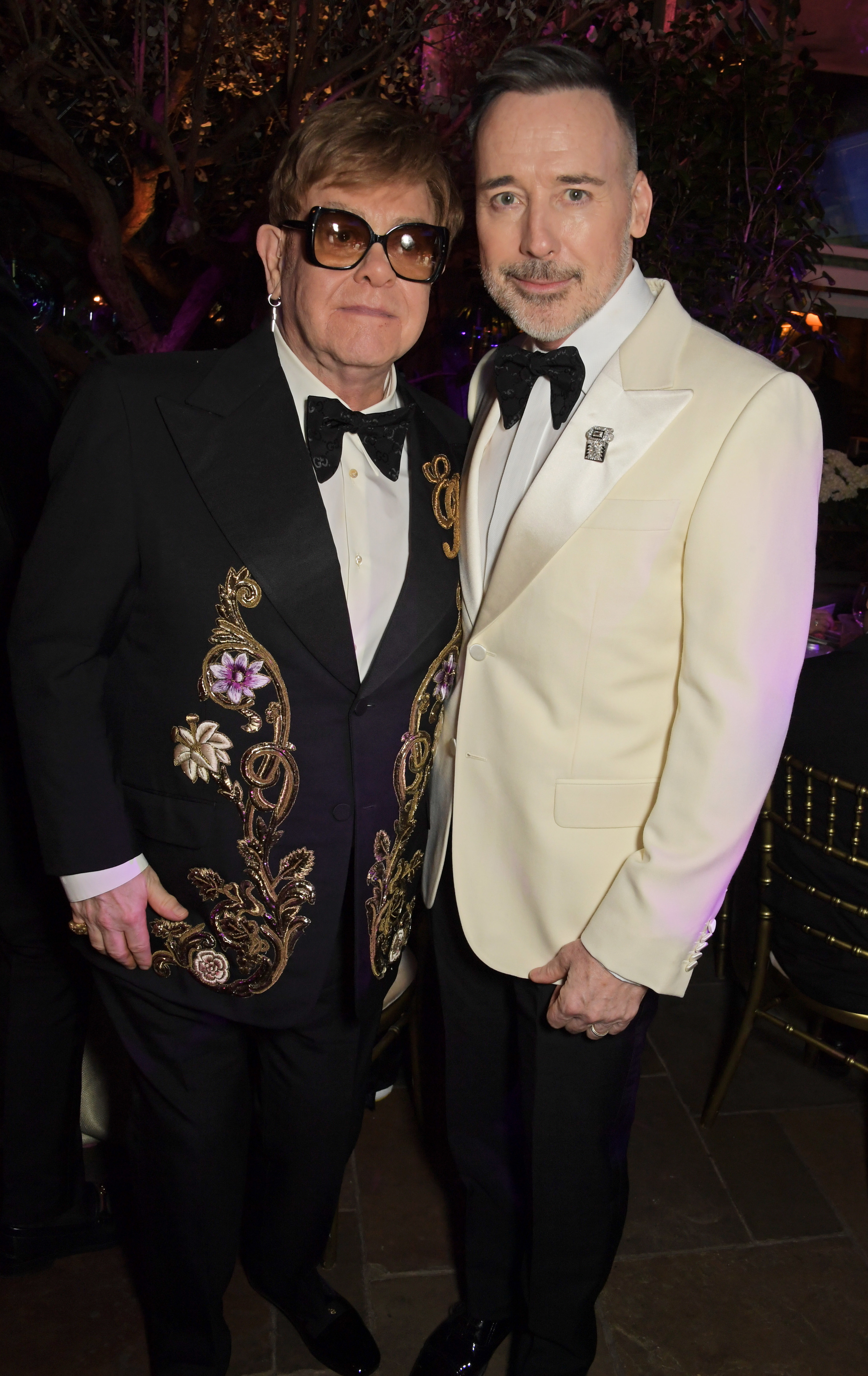 Elton John and David Furnish stand together at a formal event