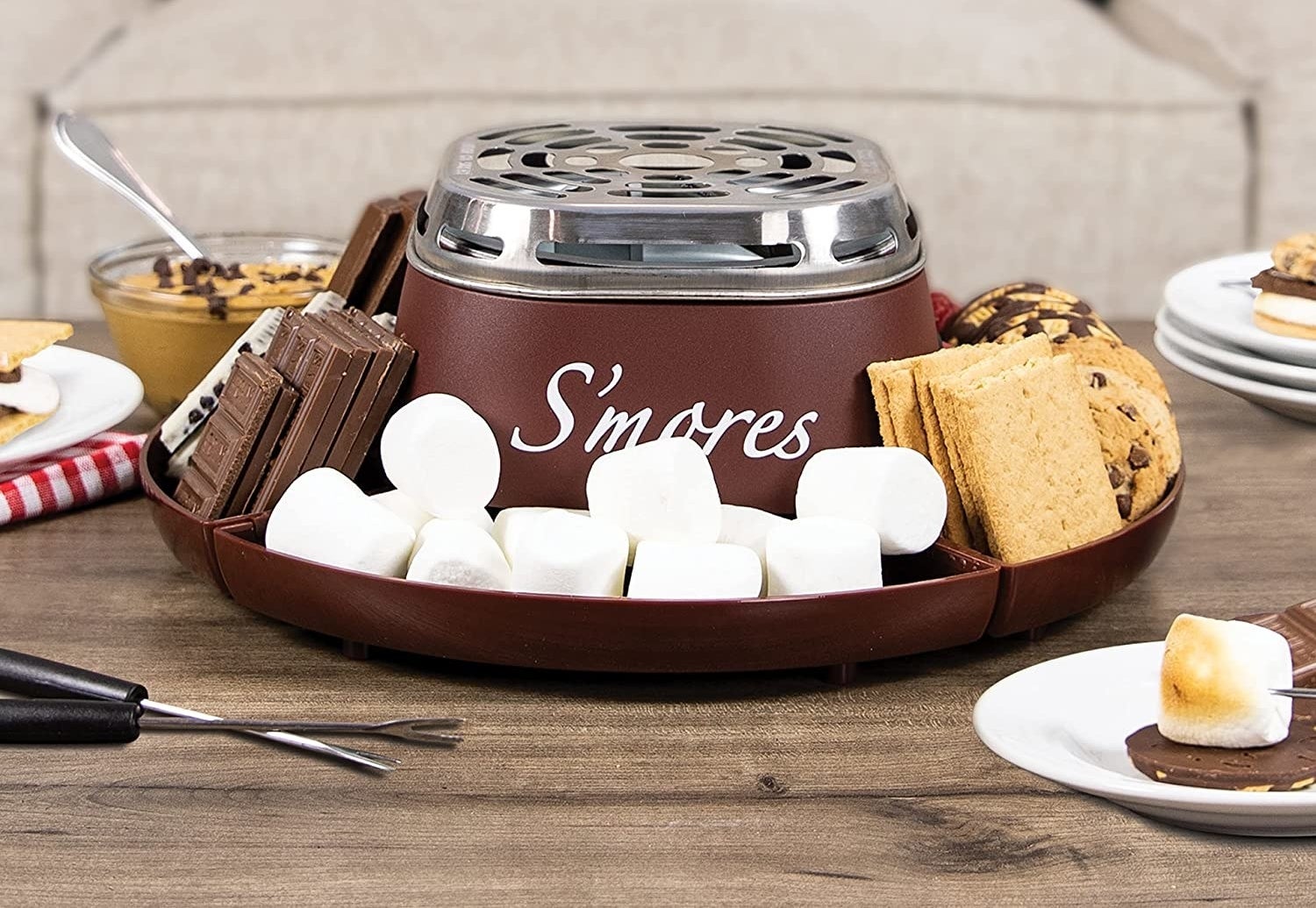 a tabletop smores kit with marshmallows, chocolate, and cookies arranged around the outside