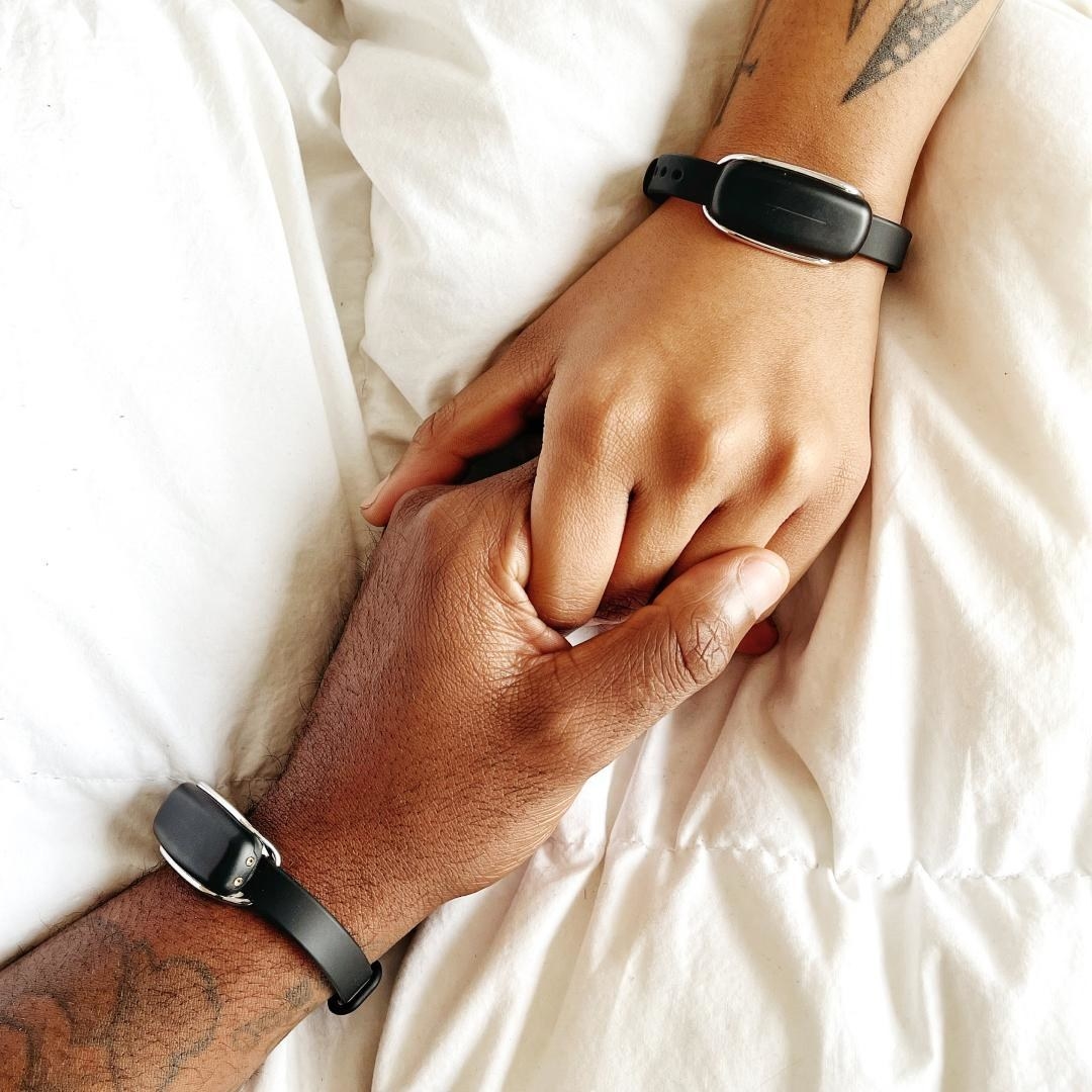 a pair of people holding hands while wearing the paired bracelets