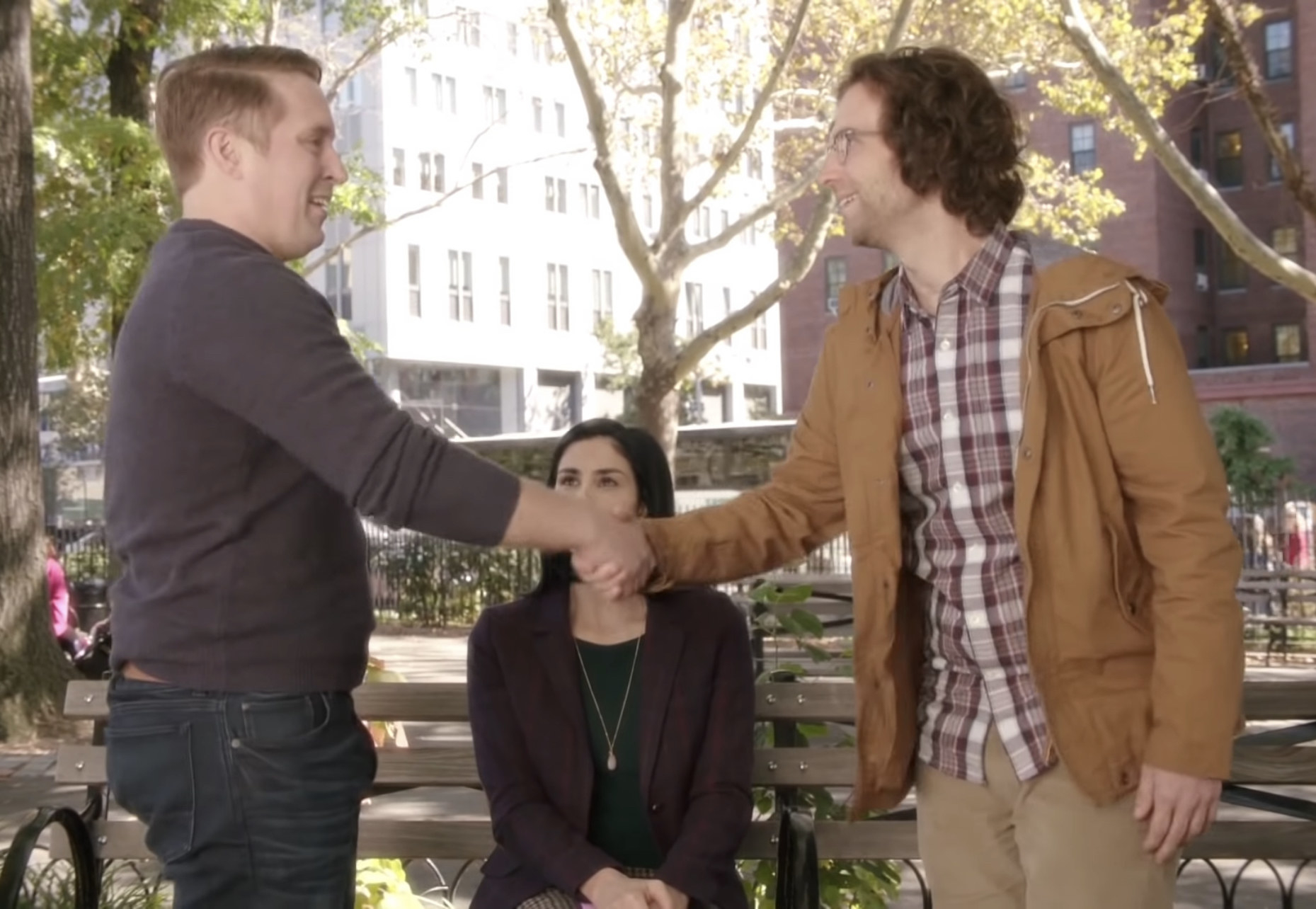 Beck Bennett and Kyle Mooney shake hands in front of Sarah Silverman